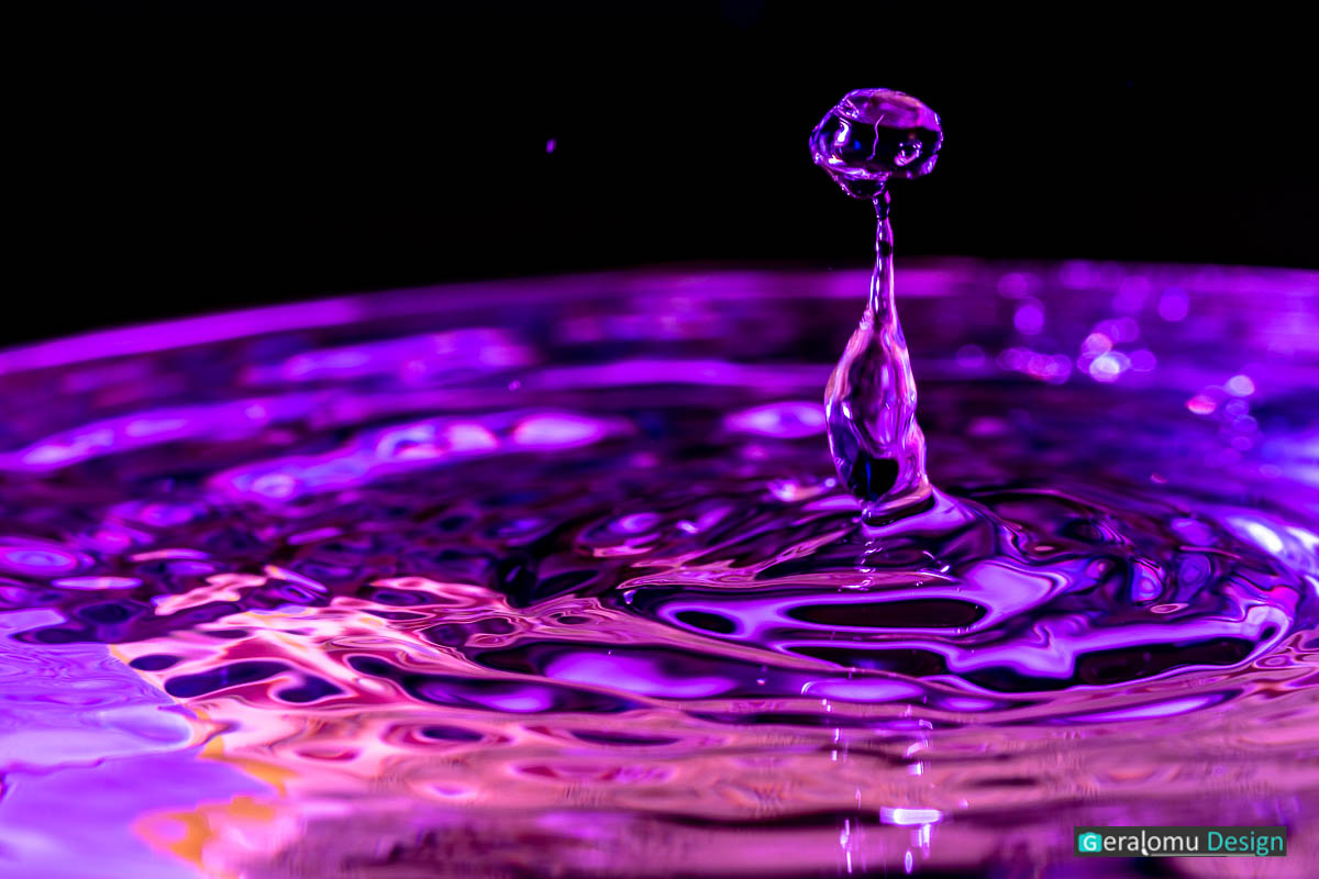 Makro Wassertropfenfotografie: Alienförmige lilafarbige Wassersäule auf der Wasseroberfläche