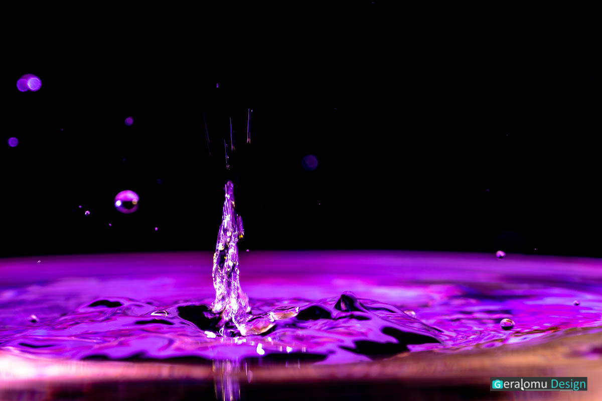 Makro Wassertropfenfotografie: Mystisch anmutende lilafarbige Wassersäule auf der Wasseroberfläche