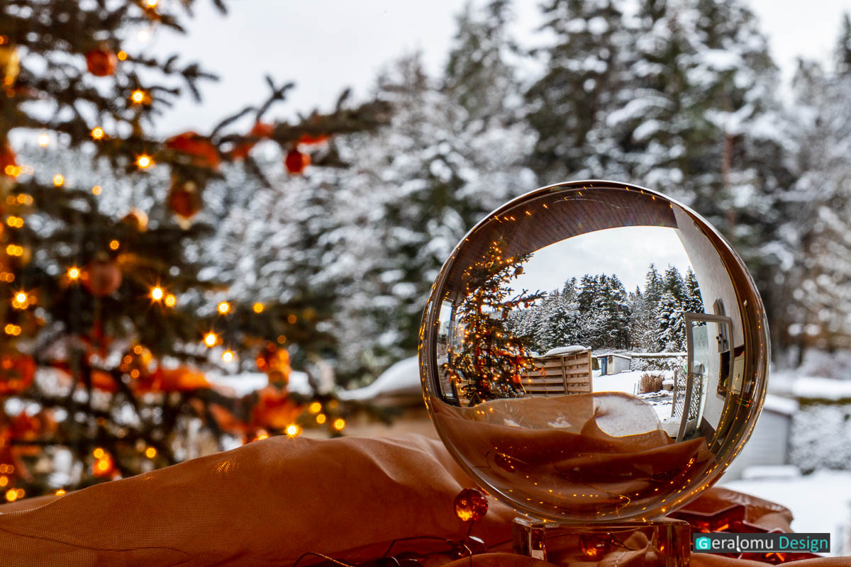 Kreative Fotografie: Eine um 180 Grad gedrehte Glaskugel mit Weihnachtsbaum vor Winterlandschaft