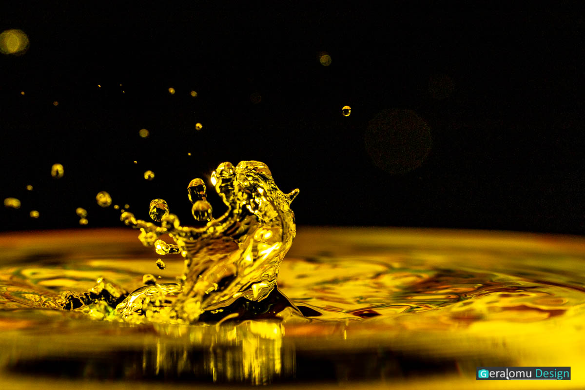 Makro Wassertropfenfotografie: Golggelbe Wassertropfenfigur nach dem Auftreffen eines Tropfen auf die Wasseroberfläche
