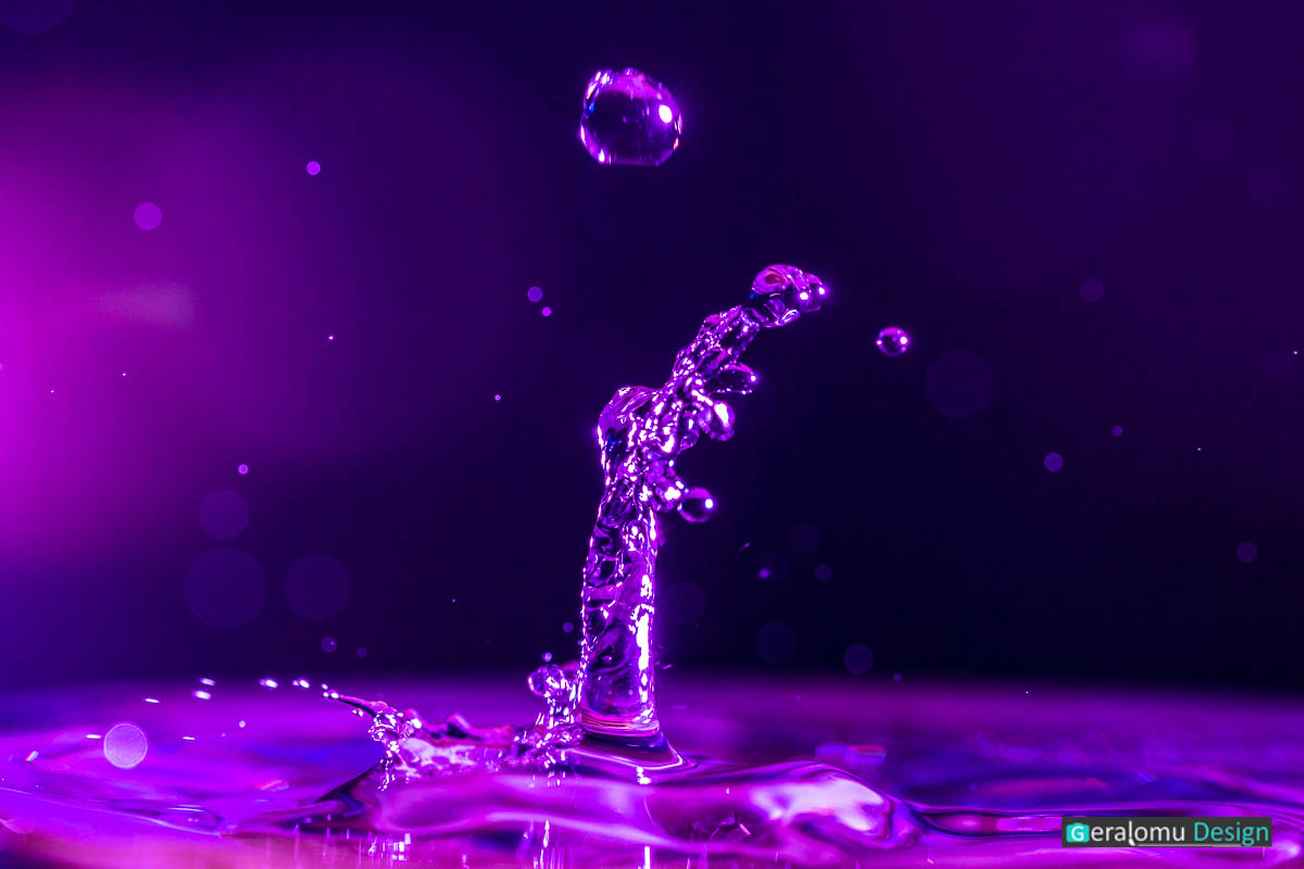Wassertropfenfotografie Makro: lilafarbige Wasserfontäne nach dem Aufprall eines Wassertropfens auf der Wasseroberfläche