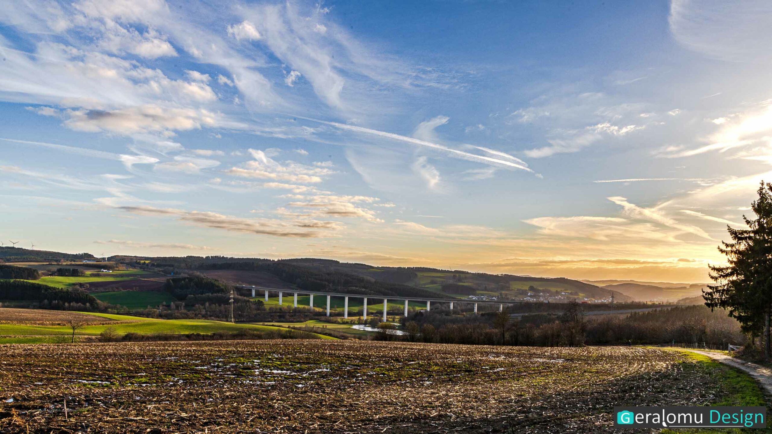 Landschaftsfotografie: Das Bild zeigt ein Eifelpanorama mit Autobahnbrücke und dem Ort Watzerath aus dem Kreis Bitburg-Prüm im Nebel und im Licht der untergehenden Sonne.