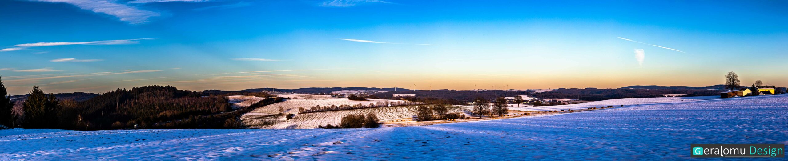 Landschaftsfotografie: Das Bild zeigt einen Panoramablick vom Goldberg beim Ort Ellwerath im Kreis Bitburg-Prüm auf schneebedeckte Landschaft im Abendsonnenschein