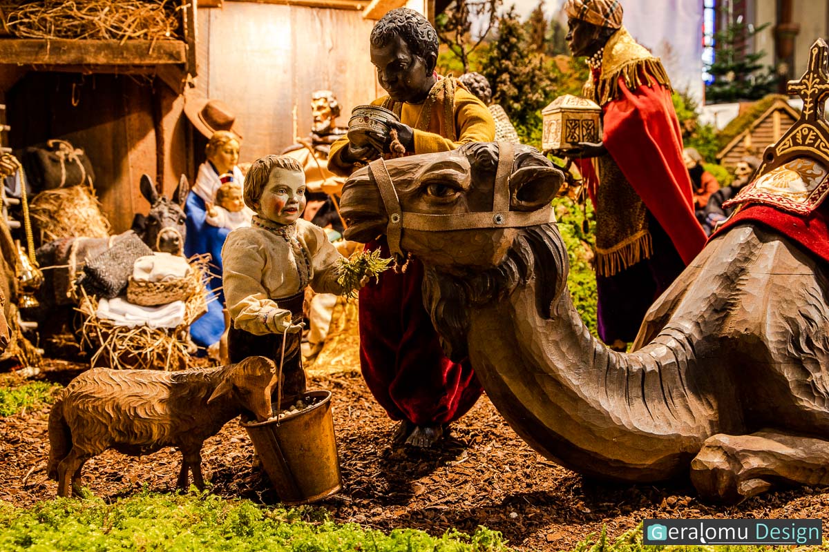 Zu sehen ist ein Junge, der ein Kamel der heiligen drei Könige füttert in der Szene Epiphanie in der historischen Weihnachtskrippe in Lichtenborn.