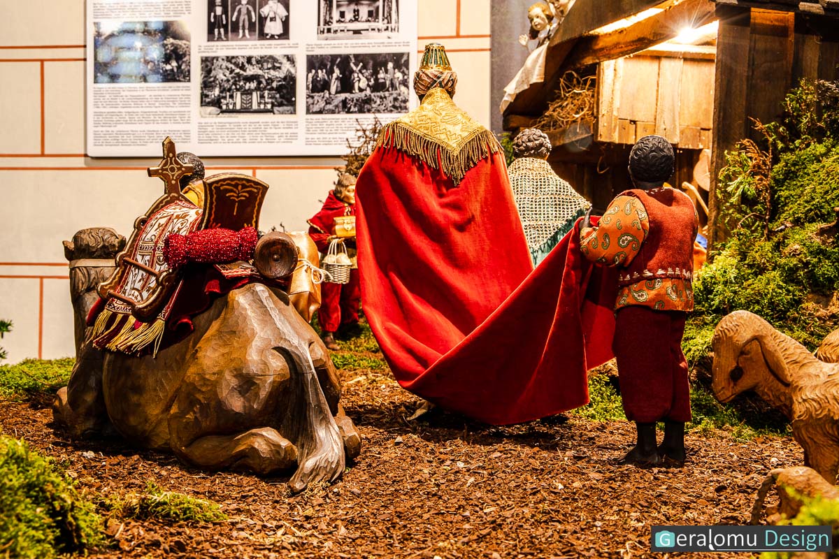 Zu sehen ist ein König mit langem roten Mantel bei der Ankunft im Stall von Bethlehem in der Szene Epiphanie in der historischen Weihnachtskrippe in Lichtenborn.