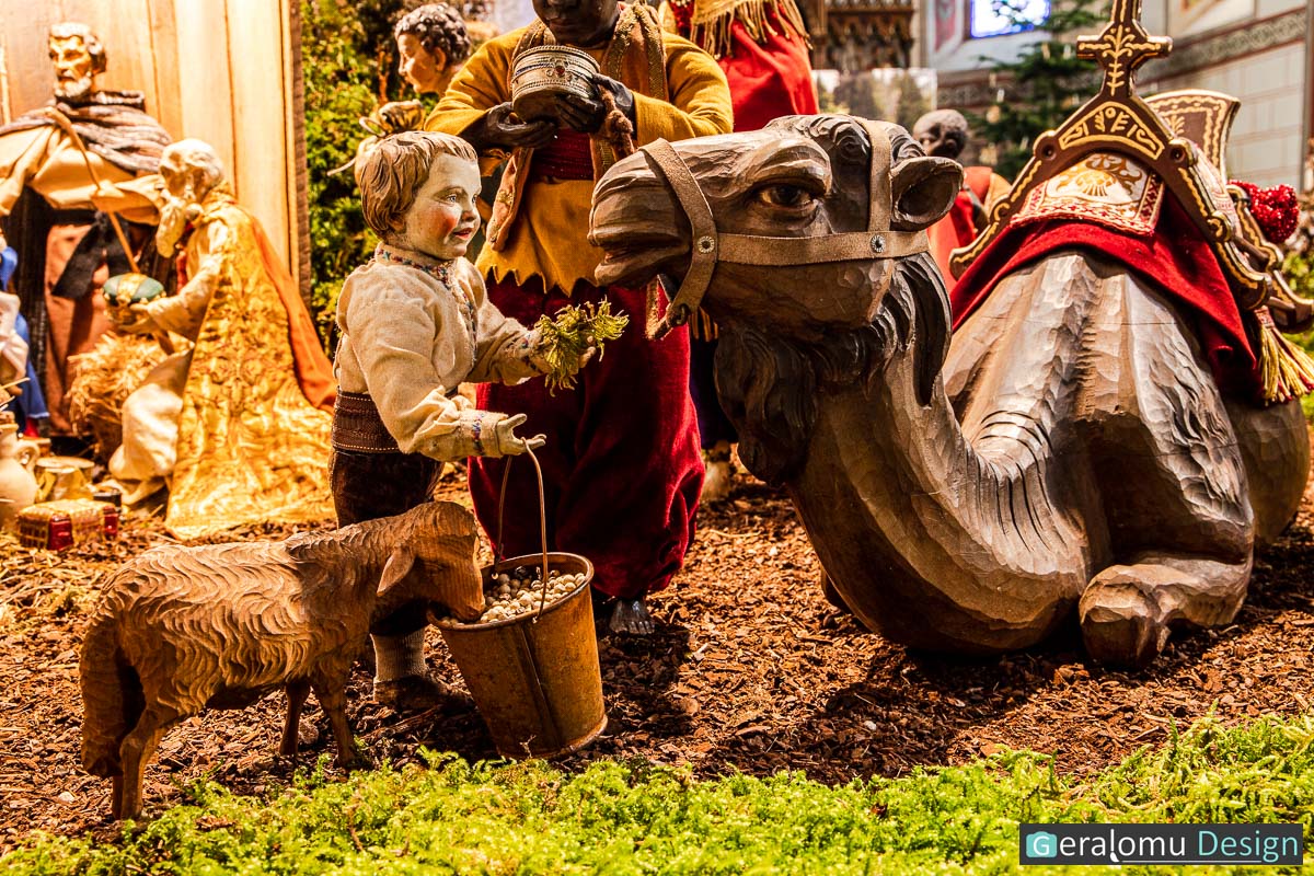 Zu sehen ist ein Junge, der ein angereistes Begleitkamel beim Stall von Bethlehem füttert in der Szene Epiphanie in der historischen Weihnachtskrippe in Lichtenborn.