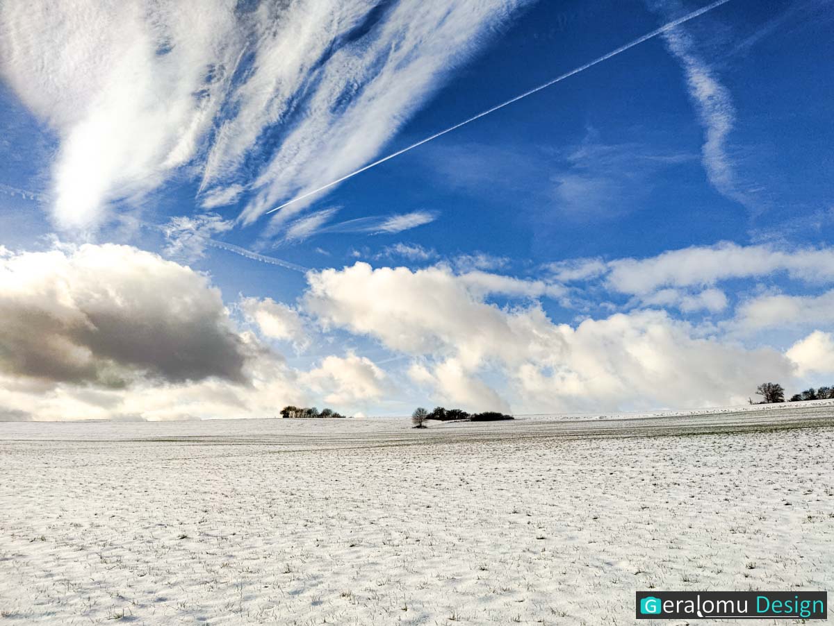 Dieses Landschaftsfoto zeigt eine schneebedeckte Winterlandschaft unter beeindruckendem Wolkengebilde in der Umgebung des Ortes Ellwerath im Eifelkreis Bitburg-Prüm.